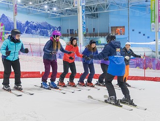 a group on people stood in a row doing on their skiing lesson on the slope