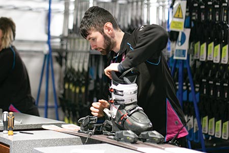 Man on a ski fitting desk, adjusting ski bindings