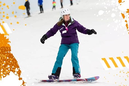 A lady snowboarding down Chill Factor<sup>e</sup> indoor slope, there are paint splatter effects on the image